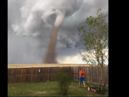 Un om cu adevărat calm! Tunde iarba, deși în spatele lui este o tornadă